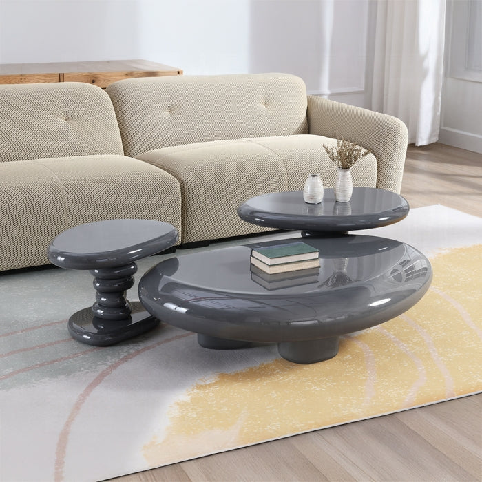 Set of three gray coffee tables in a living room setting with a beige sofa and decorative items.