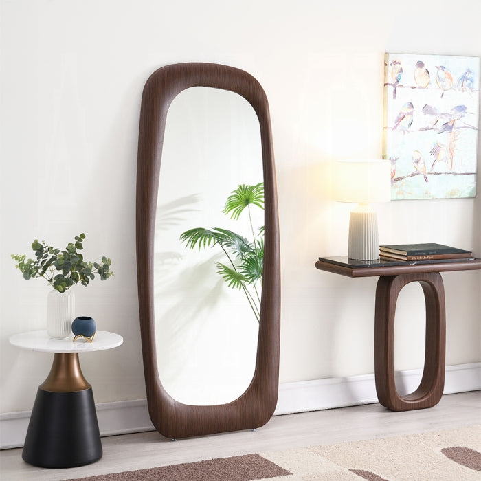 Wooden floor mirror in a room with a side table and decorative items.