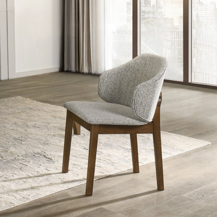 Modern chair with wooden legs and gray cushioned seat in a room with large windows.